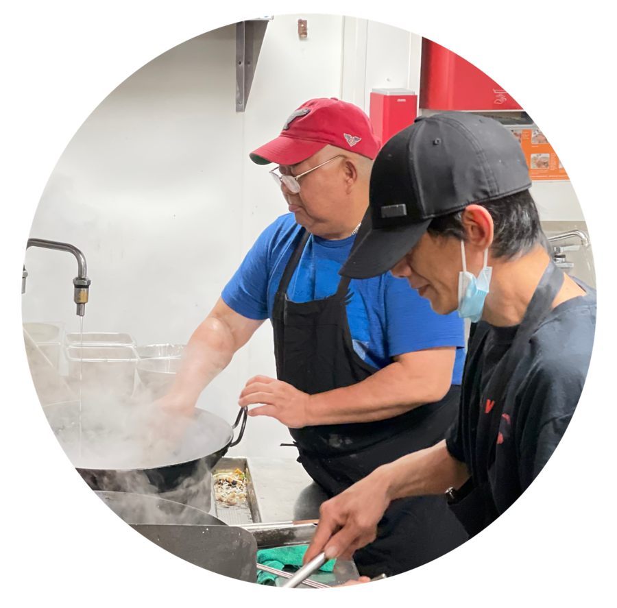 Cuisiniers au wok dans la cuisine du Piment Vert